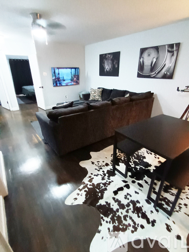 A living room with a brown couch and a cowhide rug.