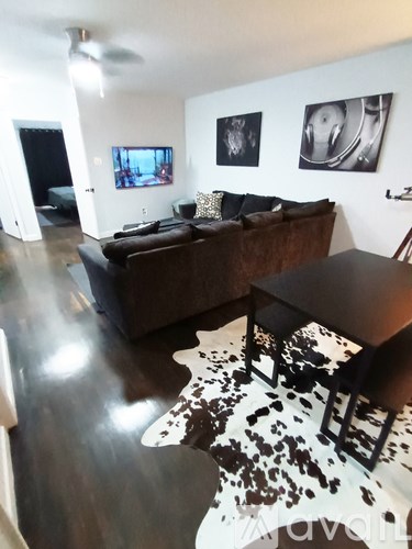 A living room with a brown couch and a cowhide rug.