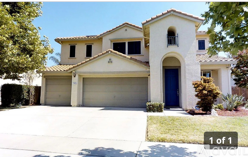 A two-story house with a blue door and garage doors.