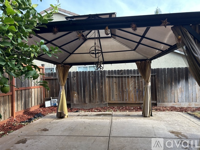 A patio with a canopy and a table with chairs underneath.