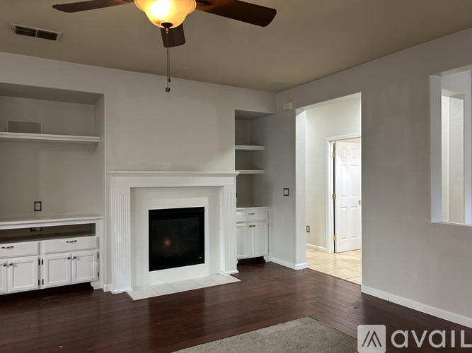 A living room with a fireplace and a ceiling fan.