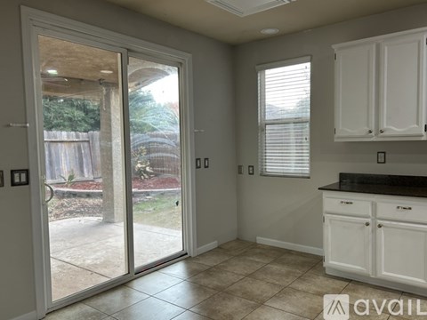 A kitchen with white cabinets and a tiled floor.