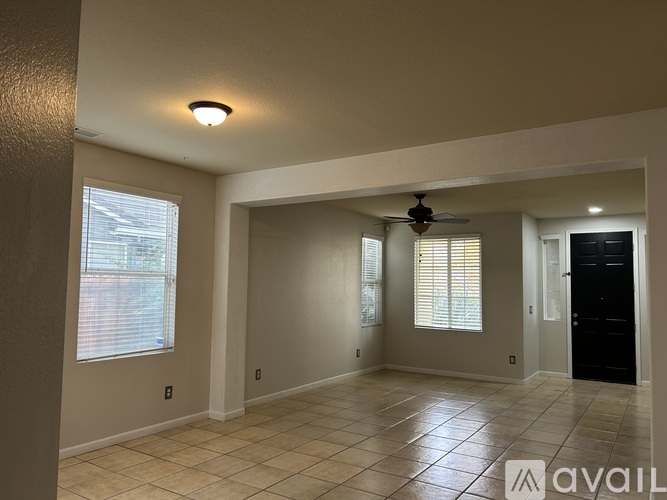 A spacious room with tiled flooring and a ceiling fan.