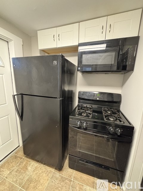 A black refrigerator and stove in a kitchen.