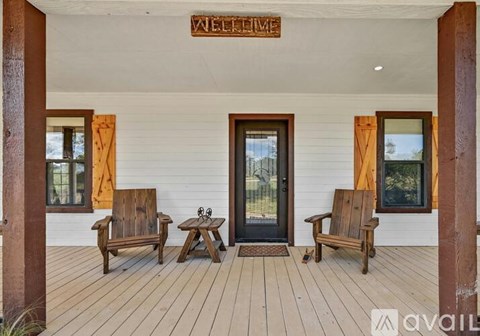 A wooden porch with a welcome sign and two chairs.