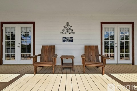 Two chairs and a table are on a porch.