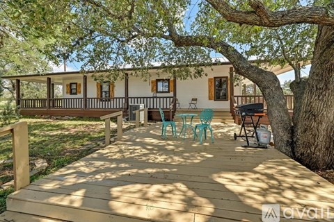A wooden deck with a table and chairs is surrounded by trees.