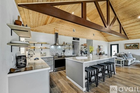 A modern kitchen with a large island and wooden ceiling beams.