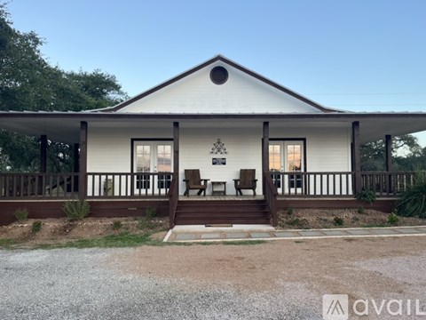 A white house with a brown porch and a logo on the front.