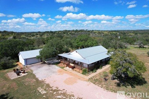 A house with a garage is surrounded by trees and grass.