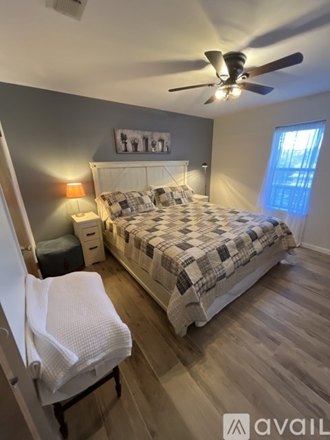 A bedroom with a bed, chair, and ceiling fan.
