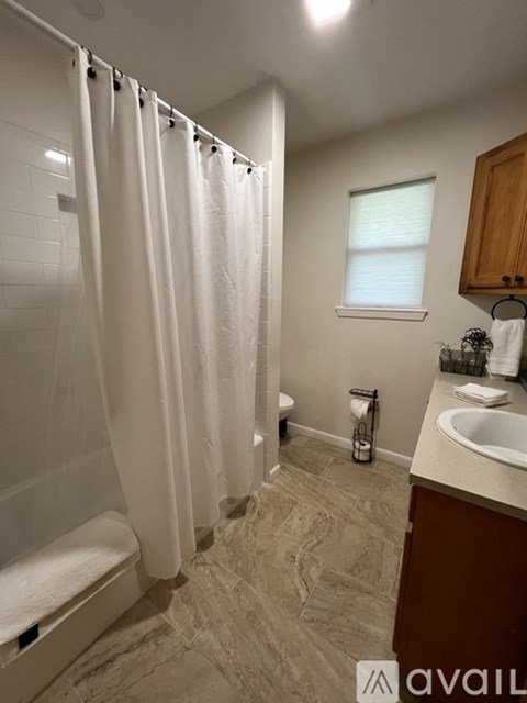 A bathroom with a white shower curtain and a tiled floor.