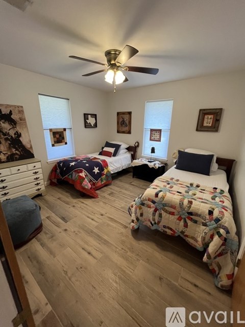 A bedroom with two beds and a ceiling fan.