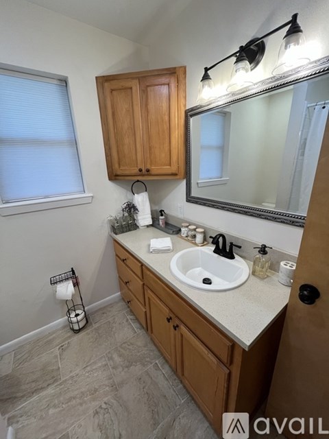 A bathroom with a sink, mirror, and wooden cabinets.
