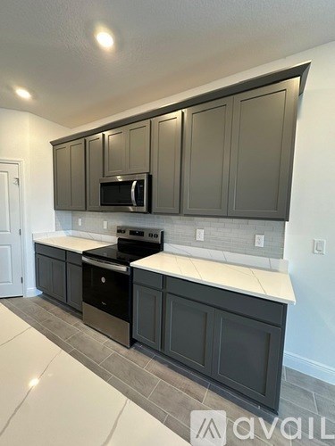 A kitchen with dark cabinets and a white countertop.