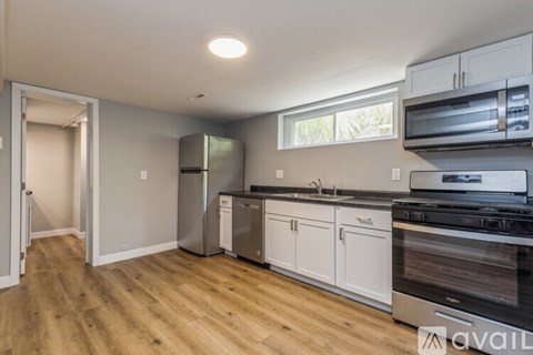 A kitchen with white cabinets and a wooden floor.