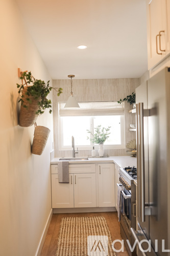 A kitchen with white cabinets and a stainless steel refrigerator.