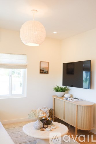 A living room with a white table and a television on the wall.