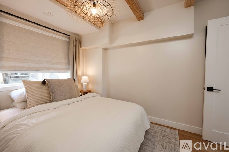 A bedroom with a large bed and a window with blinds.
