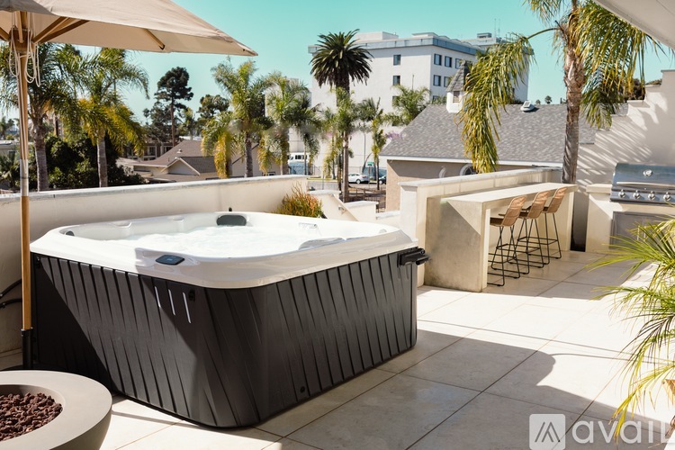 A hot tub sits on a patio with a bowl of chocolate chips and a table nearby.