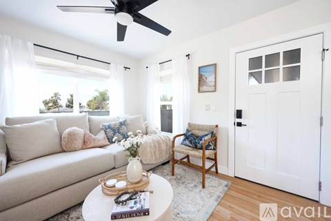 A living room with a white couch, a wooden chair, and a coffee table with a vase on it.
