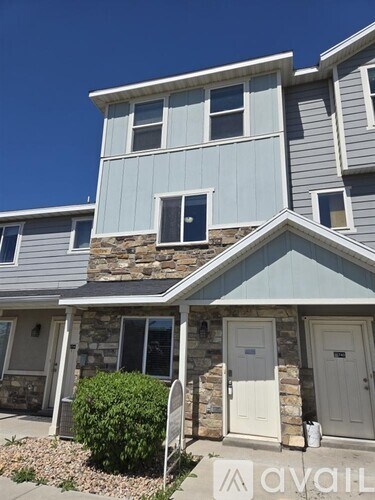 A house with a grey and white exterior and a stone wall.
