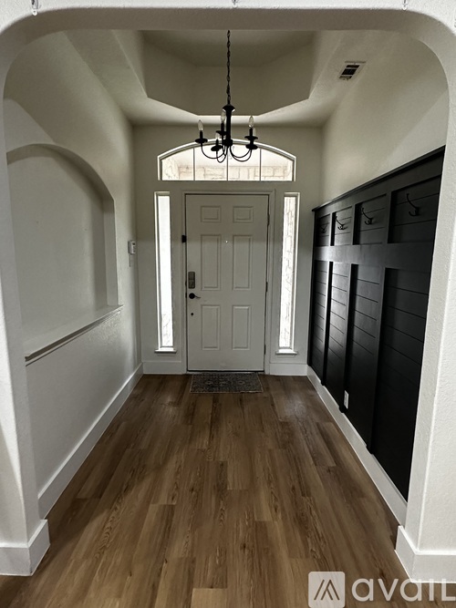A hallway with a white door and wooden floor.