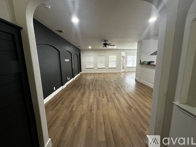 A spacious room with wooden flooring and a ceiling fan.