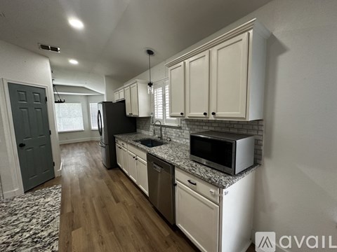A kitchen with white cabinets and a black refrigerator.