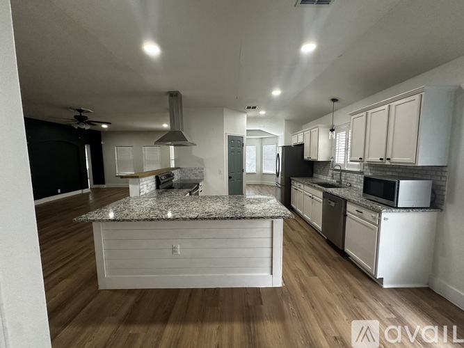 A kitchen with a granite countertop and wooden flooring.