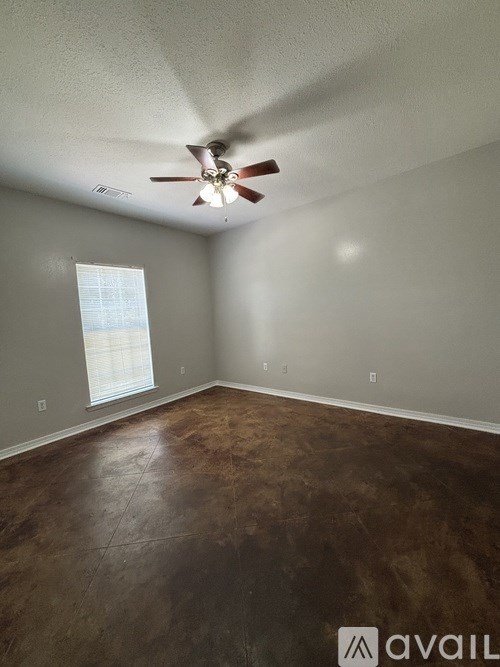 A room with a ceiling fan and brown flooring.