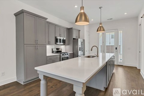 A kitchen with a large island and grey cabinets.