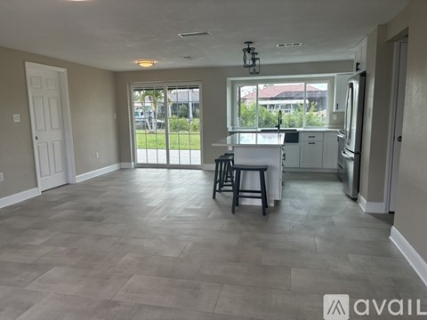 A kitchen area with a bar stool and a refrigerator.