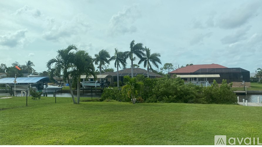 A grassy area with palm trees and a building in the background.