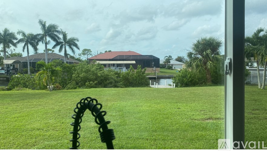A grassy field with a building and palm trees in the background.