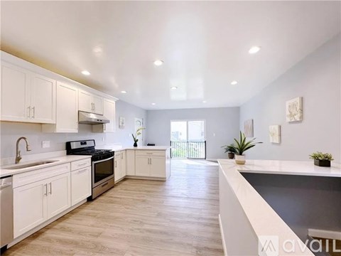 A modern kitchen with white cabinets and a wooden floor.