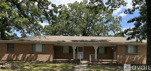 A house with a porch and a tree in front of it.