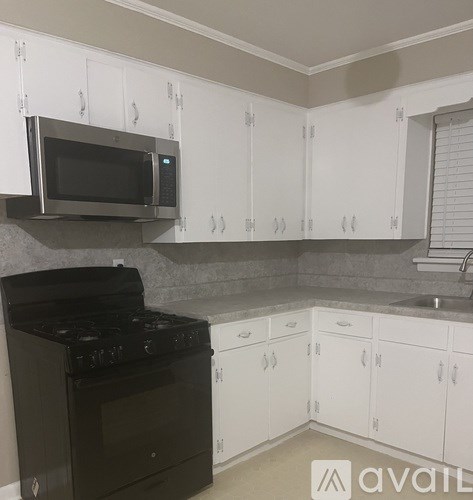 A kitchen with white cabinets and a black stove top oven.