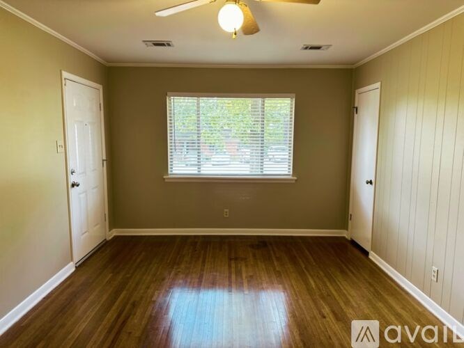 A room with wooden floors and a window with blinds.