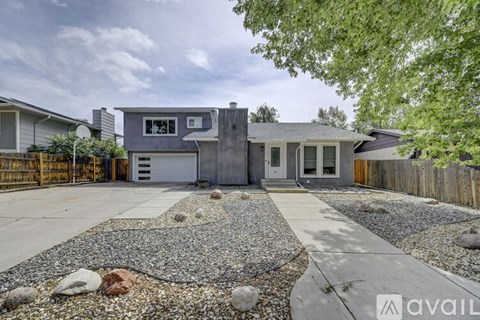A modern house with a gravel driveway in front.