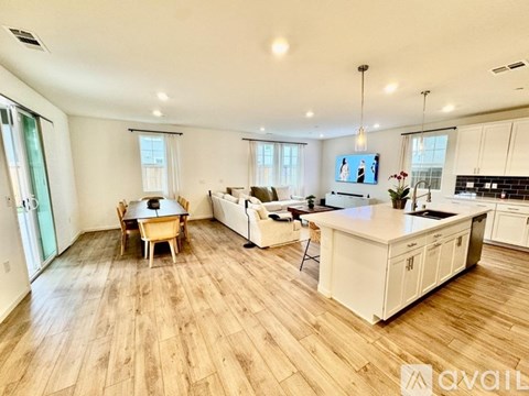 A spacious living room with a dining table and a kitchen area.