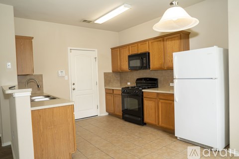 A kitchen with a white fridge, black stove and wooden cabinets.