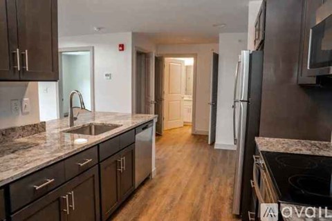 A kitchen with dark wood cabinets and a marble countertop.