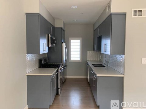 A kitchen with grey cabinets and a white countertop.