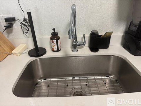 A kitchen sink with a soap dispenser and a black container.