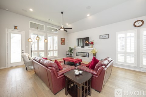 A living room with a red couch and a wooden table.