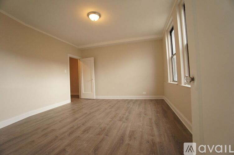 A room with wooden flooring and a window on the right side.