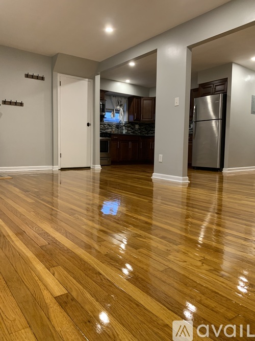 A kitchen with a refrigerator and wooden floors.