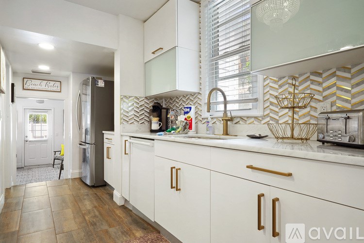 A kitchen with white cabinets and a wooden floor.