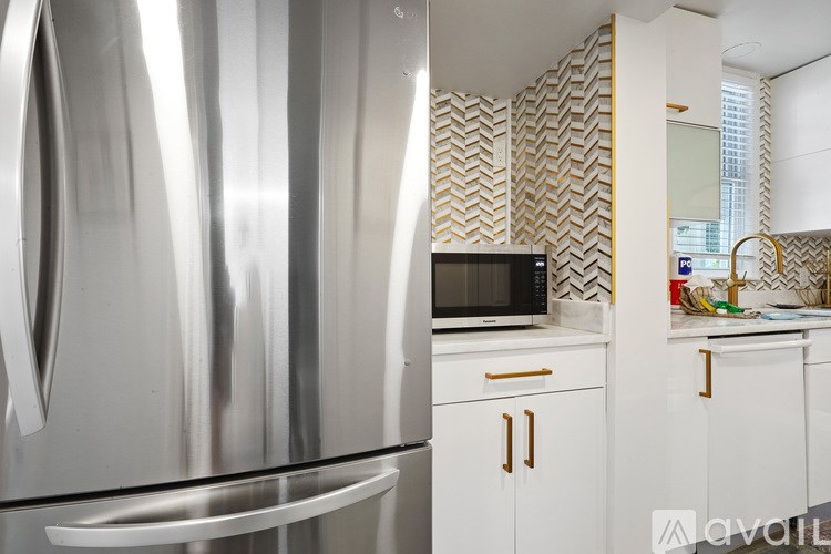 A stainless steel refrigerator in a kitchen with a microwave on the counter.